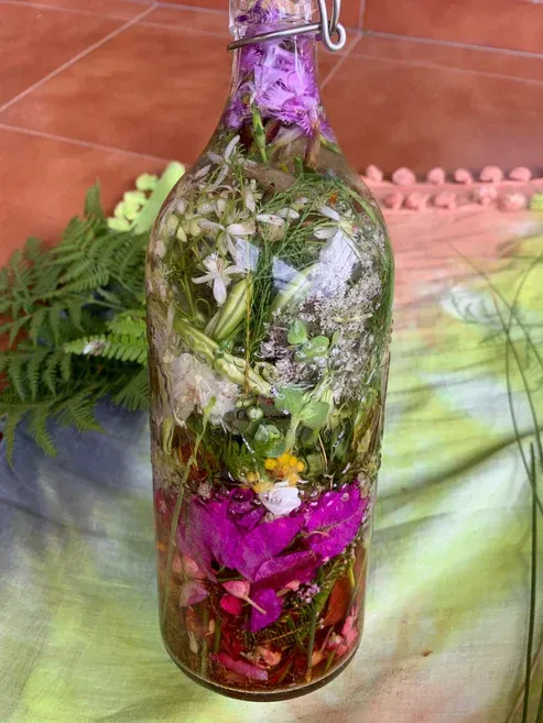 Agua de Florida. Op een tafel staat een fles gevuld met bloemen en kruiden.