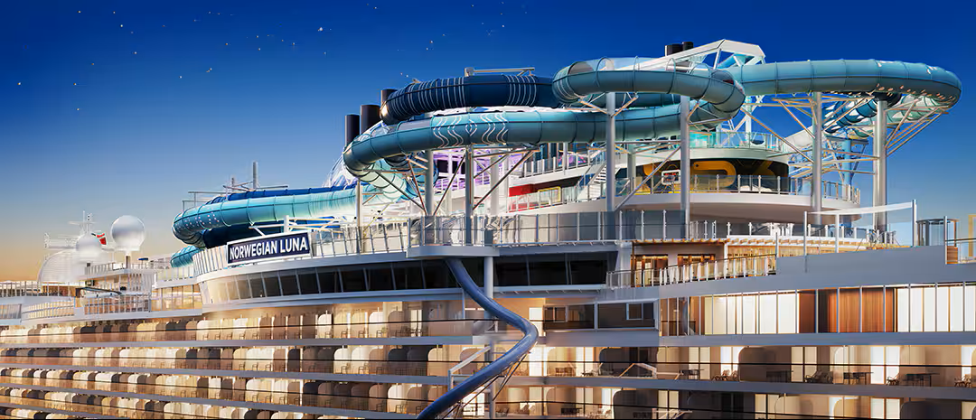 A modern cruise ship with water slides against a night sky.