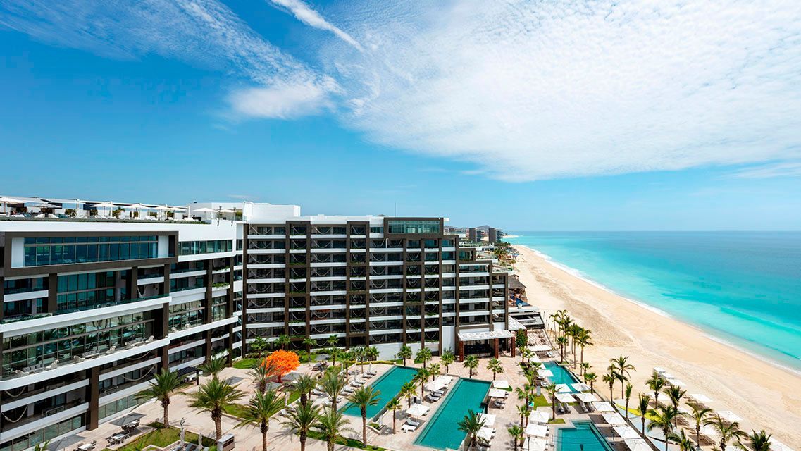 Hotel resort overlooking a beach and ocean on a sunny day.