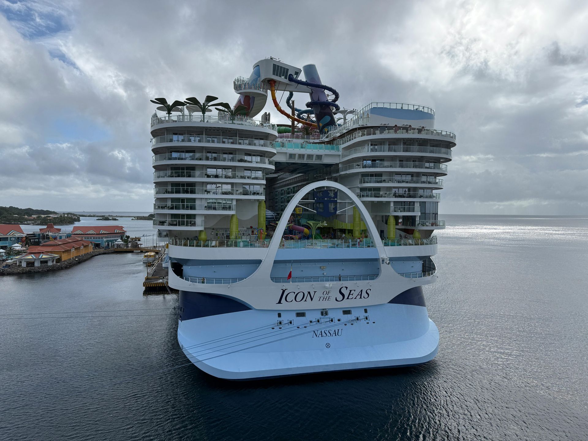 Rear view of Icon of the Seas cruise ship docked, with water slides and the ship's name visible.