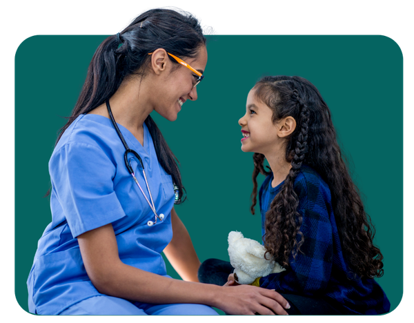 Nurse in blue scrubs smiles at a child holding a stuffed animal, both looking at each other.