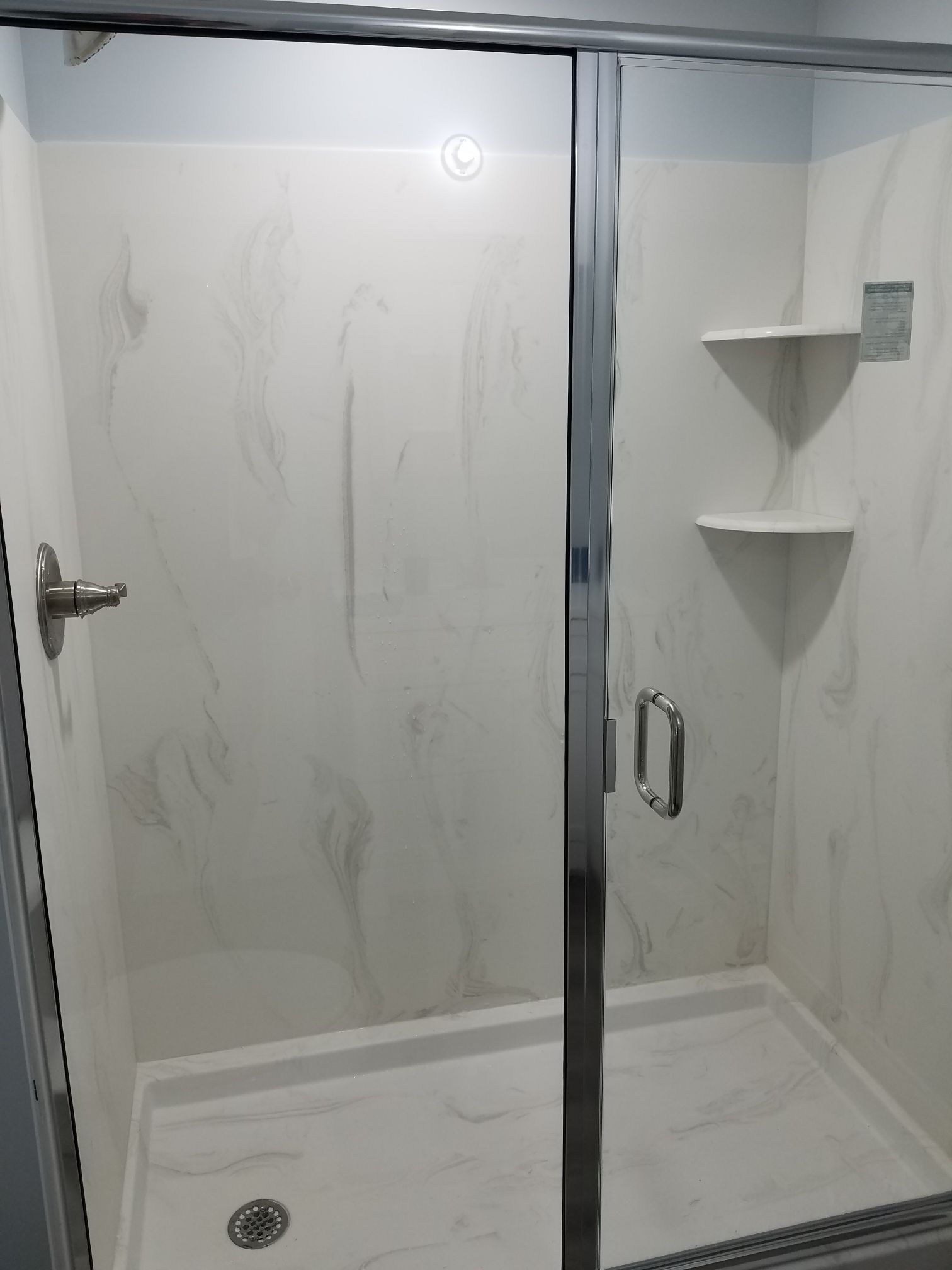 a shower with a sliding glass door and shelves