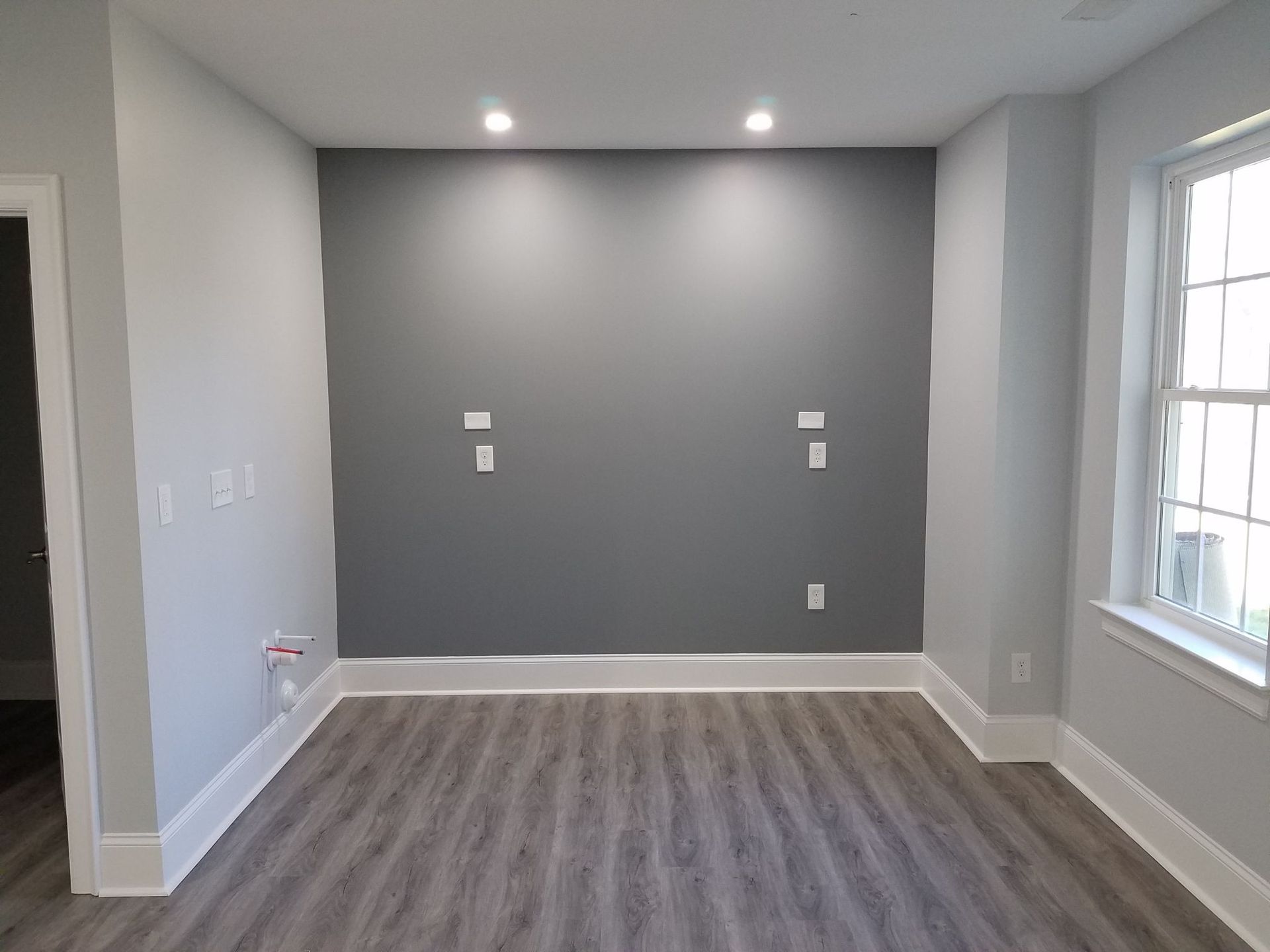 an empty room with gray walls and a window