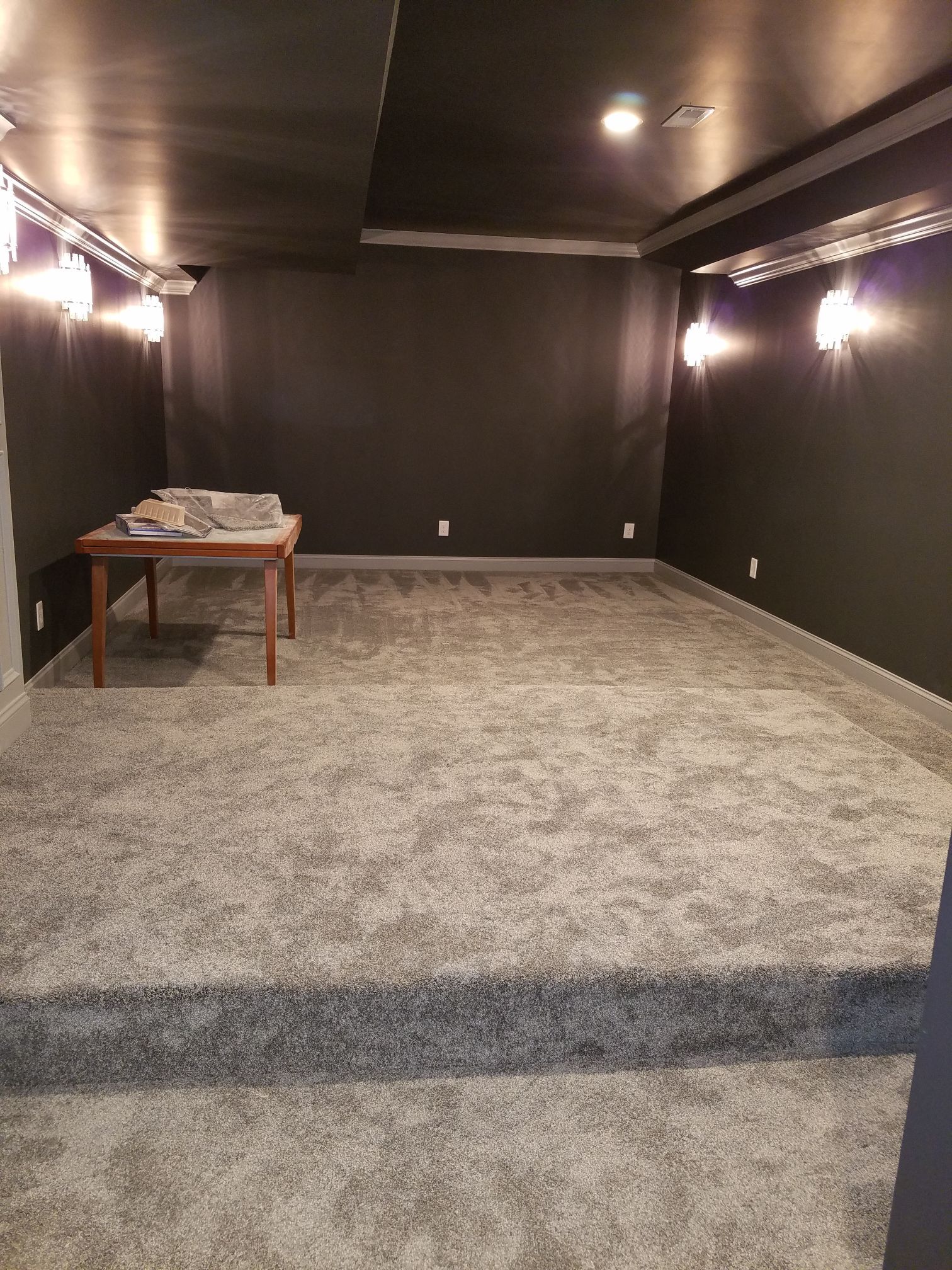 an empty room with a gray carpet and black walls