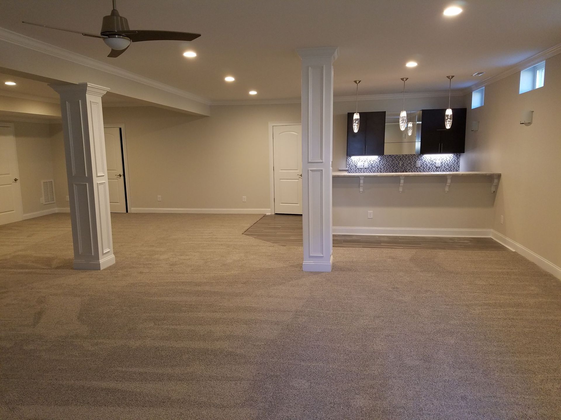 an empty room with a ceiling fan and a bar