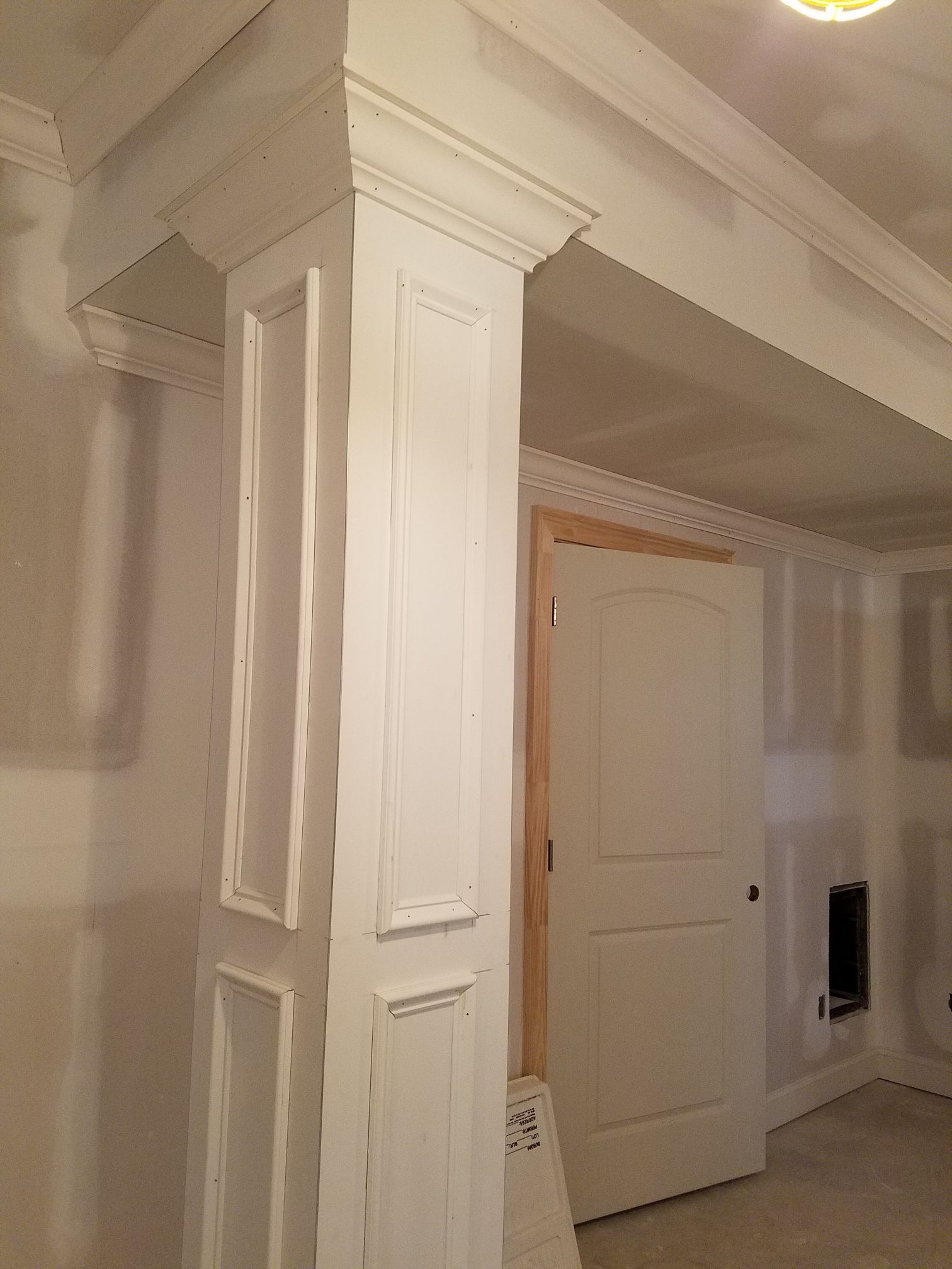 a white pillar in a room with a door