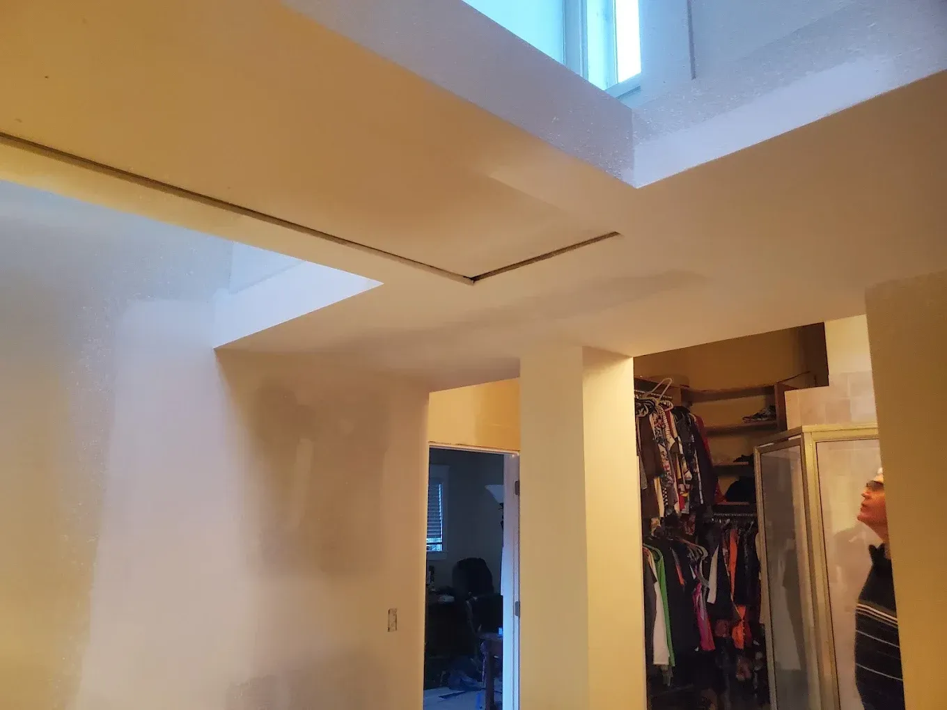 Interior view, high ceiling with skylight and closet. Beige walls and a person visible in the closet doorway.