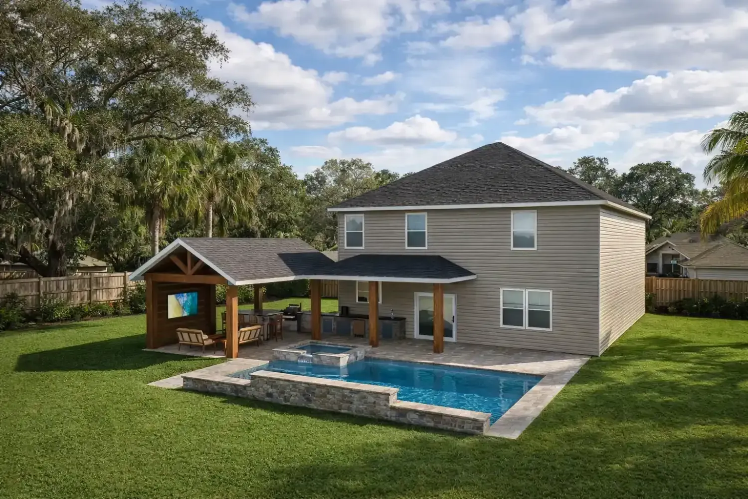 Backyard view of a two-story tan house with a covered patio, outdoor kitchen, and a rectangular swimming pool.