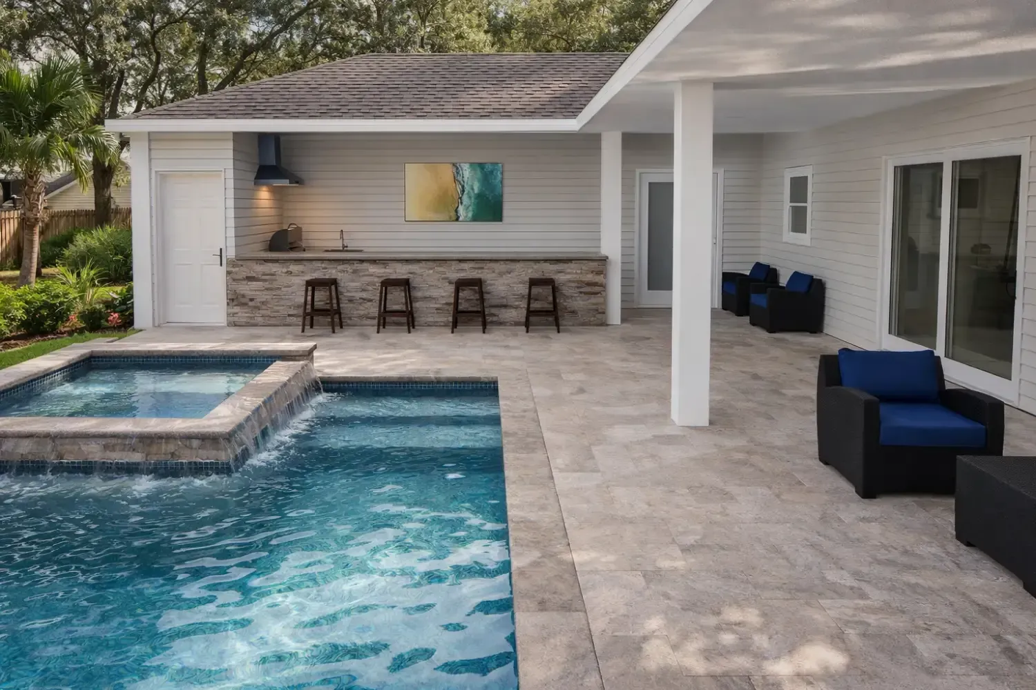 A poolside patio with a stone bar, outdoor seating, and a spa overlooking a swimming pool on a sunny day.