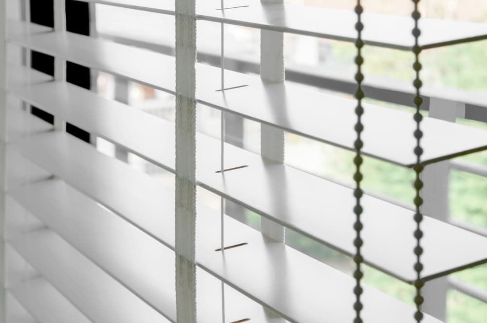A Close up Of a White Wooden Blind on A Window — More on the Floor in Wollongong, NSW