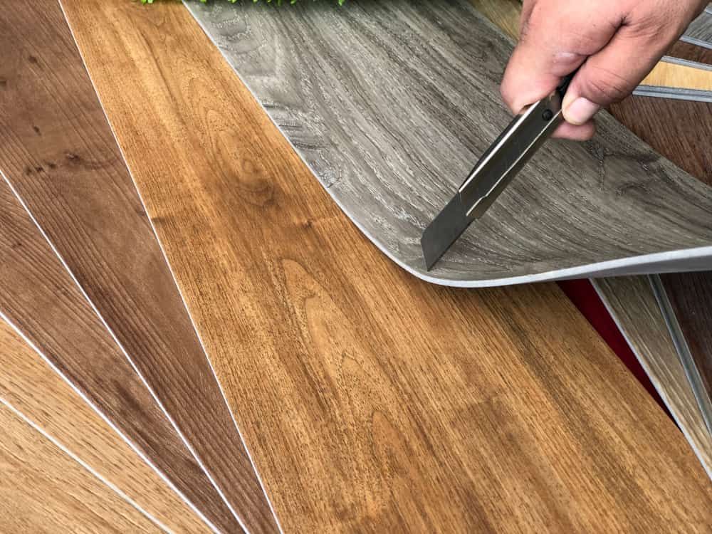 Close-Up of A Hand Holding a Cutter Close to Vinyl Flooring — More on the Floor in Barrack Heights, NSW