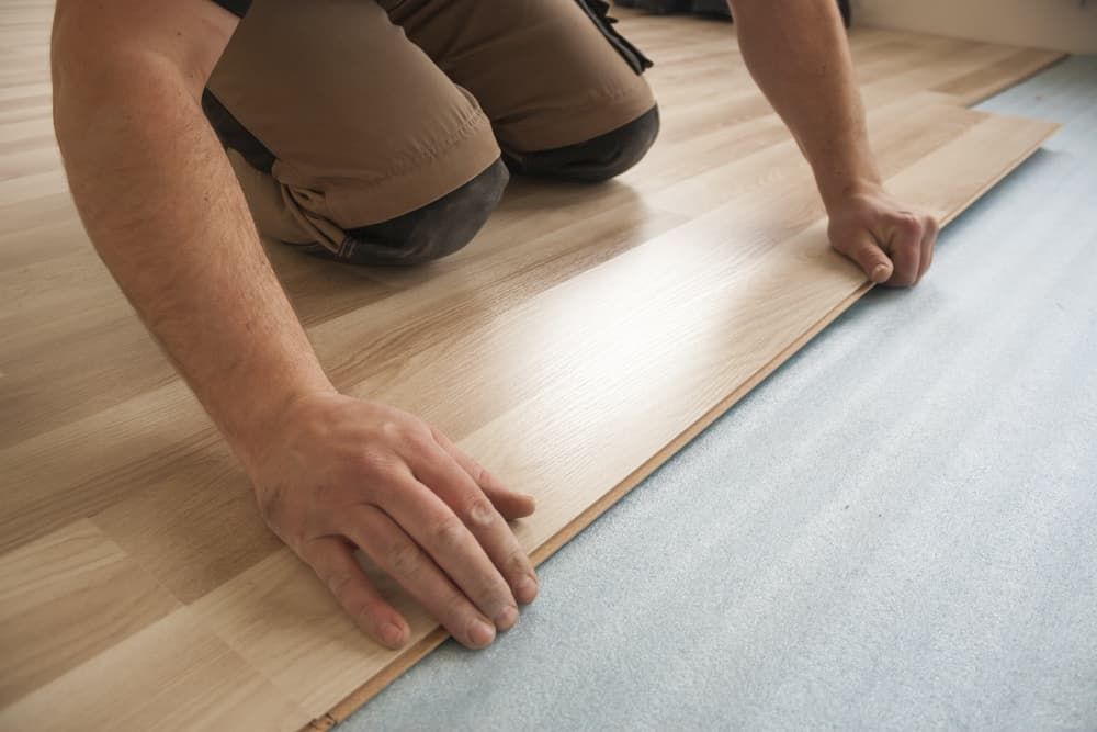 A Man Is Kneeling Down to Install a Wooden Floor — More on the Floor in Barrack Heights, NSW
