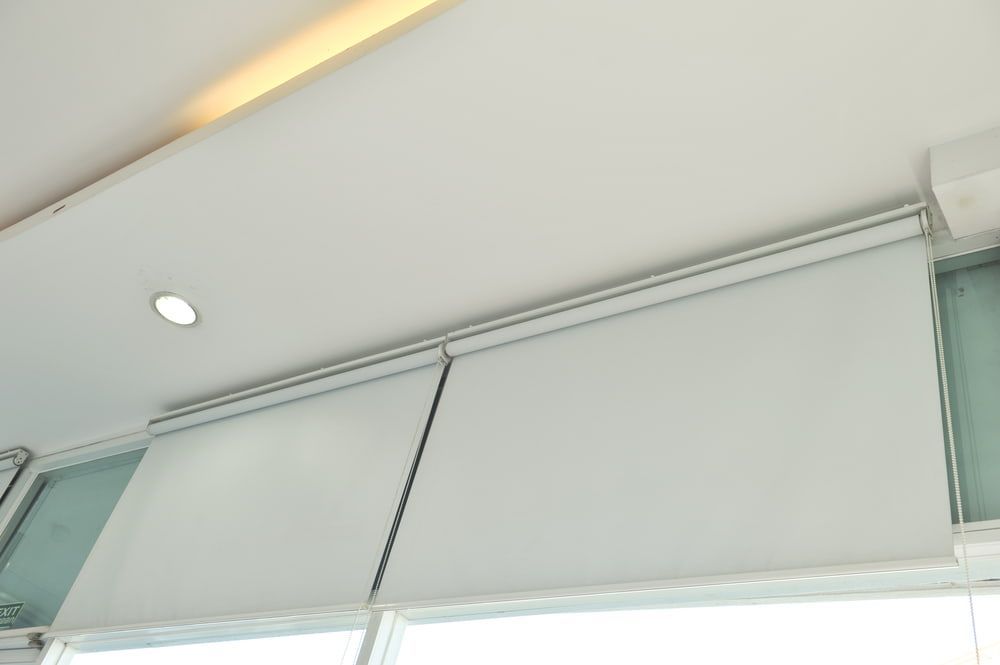 A Close up Of a White Roller Blind on A Window — More on the Floor in Barrack Heights, NSW
