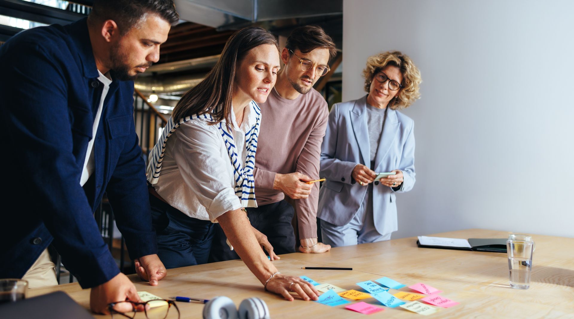 A group of people are standing around a table with sticky notes on it.