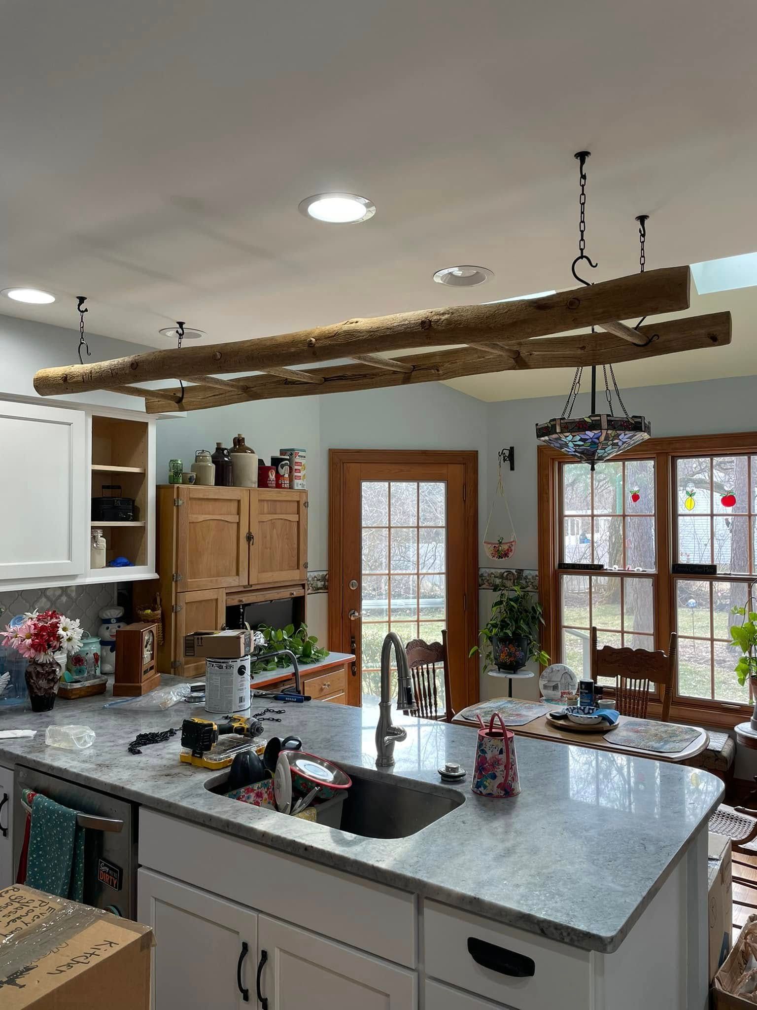 Kitchen with a granite countertop island, wooden beam light fixture, cabinets, and a window.