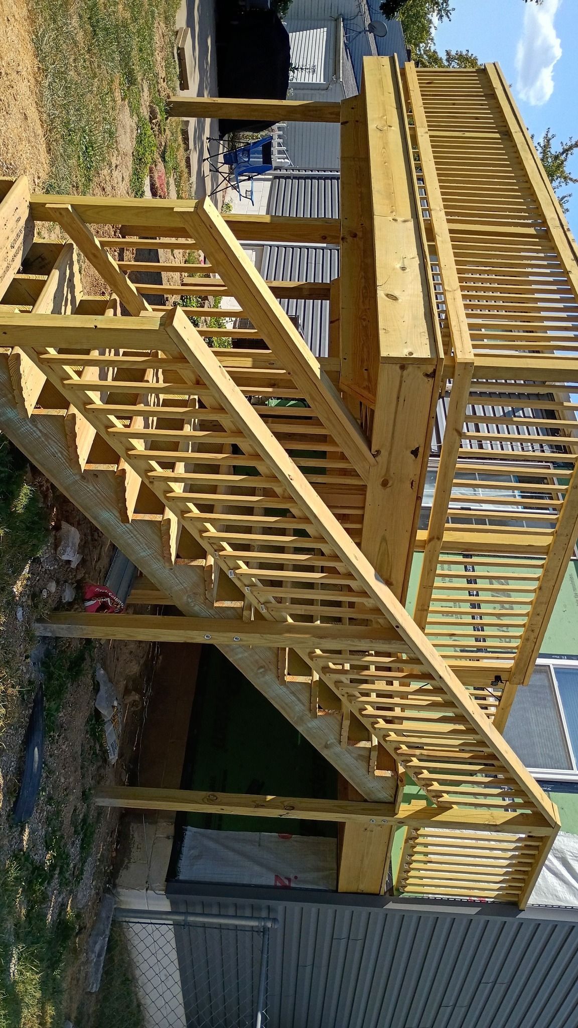 Wooden deck with stairs, built outdoors. Yellowish-brown wood.