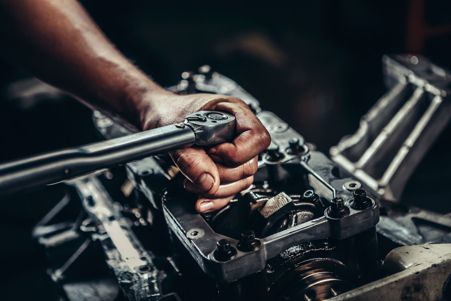 A man is working on a car engine with a wrench.