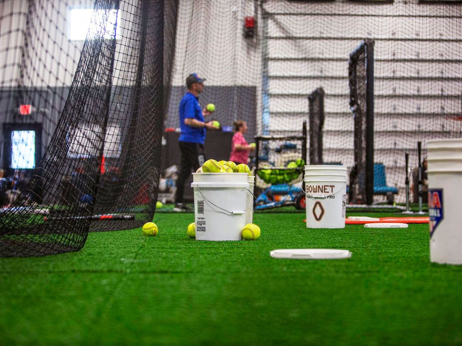 A coach is throwing softballs balls at Home Turf in Valparaiso IN.