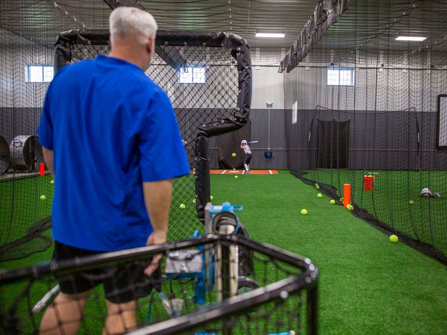 Coaches throwing softball batting practice at Home Turf.