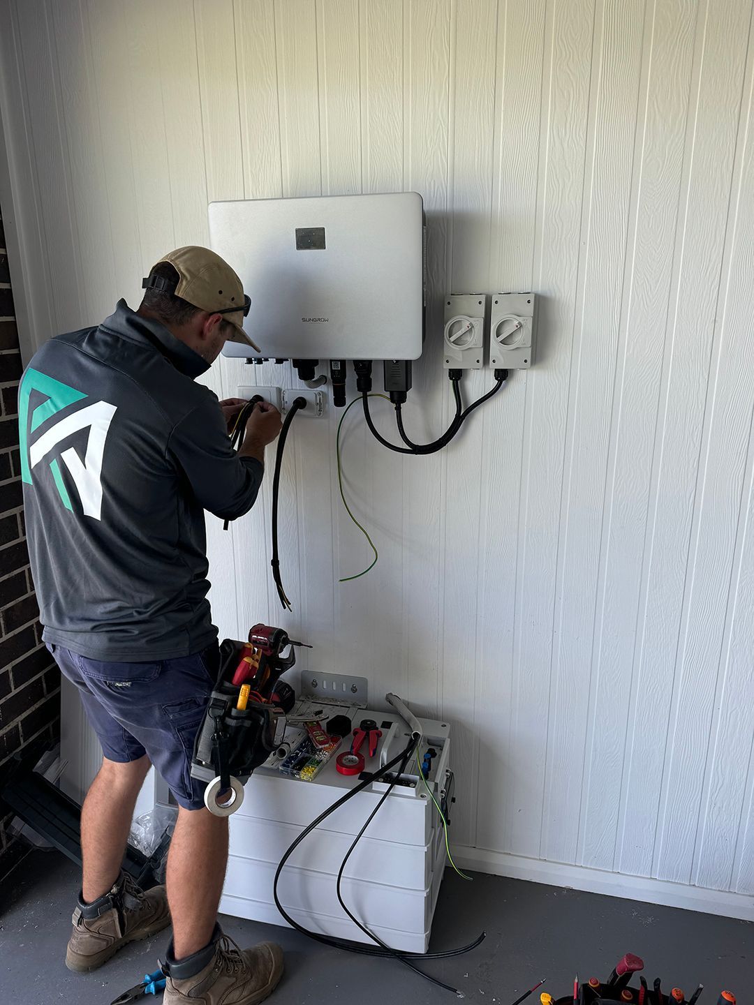 A Man Is Working On A Solar Panel In A Garage — Rid-Arc Electrical In Tamworth, NSW