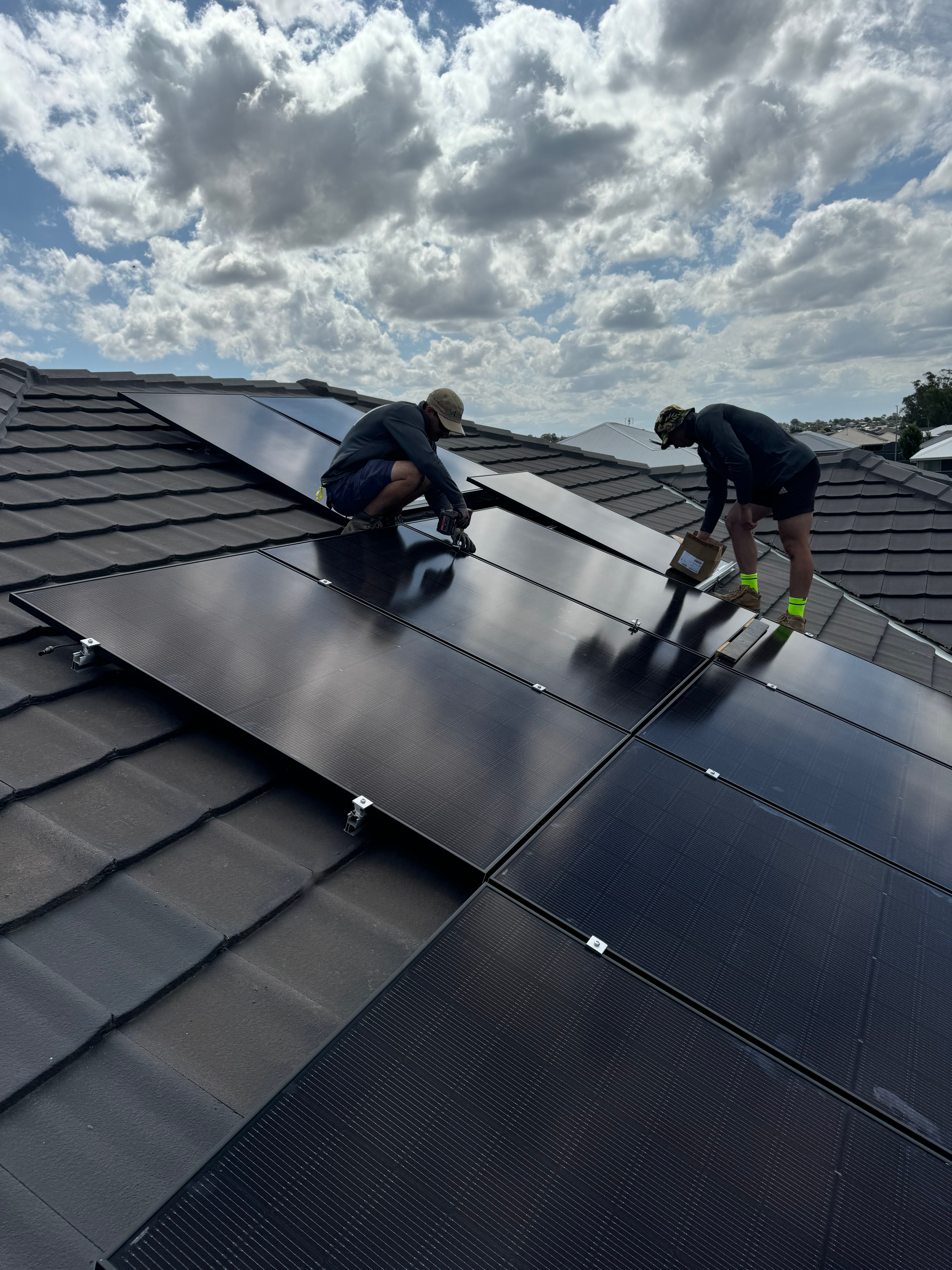 Two Men Working On A Bunch Of Solar Panels On A Roof — Rid-Arc Electrical In Tamworth, NSW