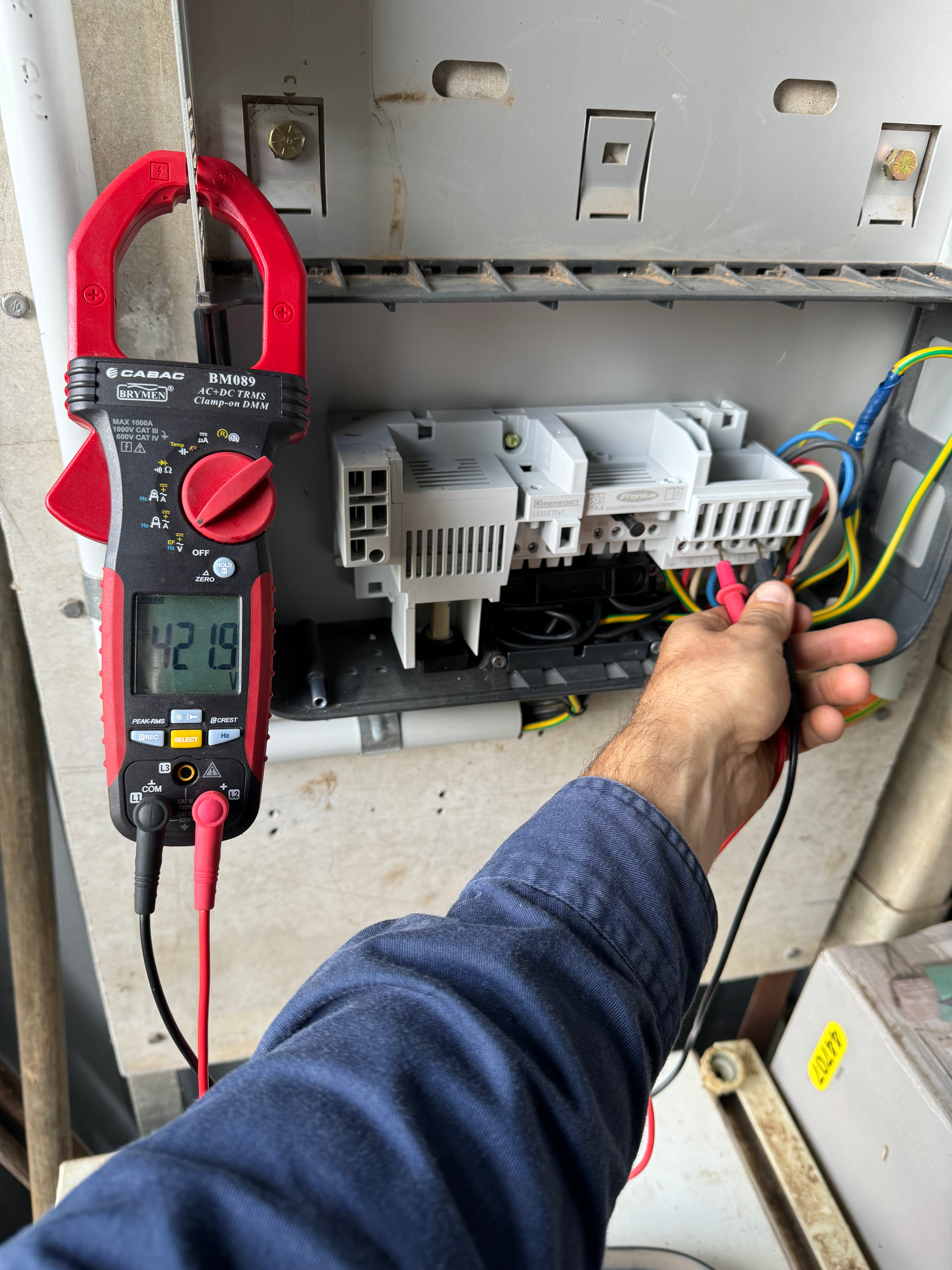 A Man Is Pluggin Wires Into A Wall — Rid-Arc Electrical In Tamworth, NSW