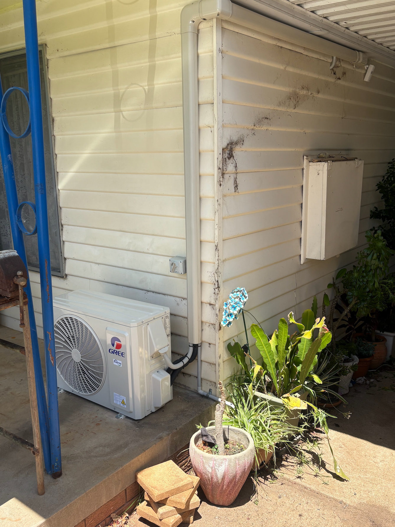 A Fan Is Sitting On The Side Of A House Next To A Potted Plant — Rid-Arc Electrical In Tamworth, NSW