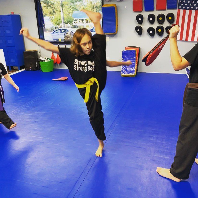 Kids practicing high kicks in martial arts class