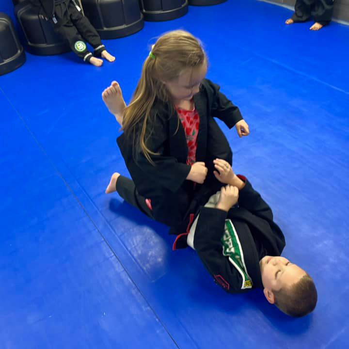 a boy and a girl are wrestling on a blue mat