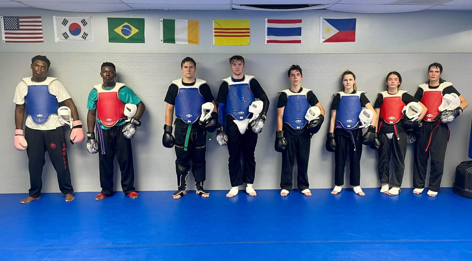 A group of people are standing in a room with flags on the wall.