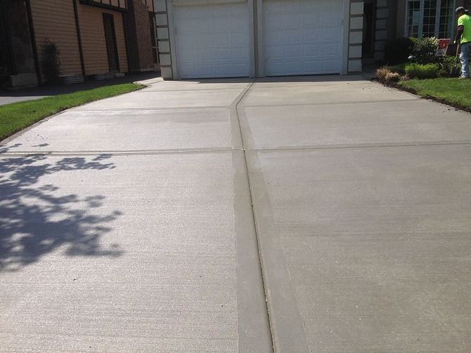 Concrete driveway leading to a two-car garage, with a shadow cast on the left side.