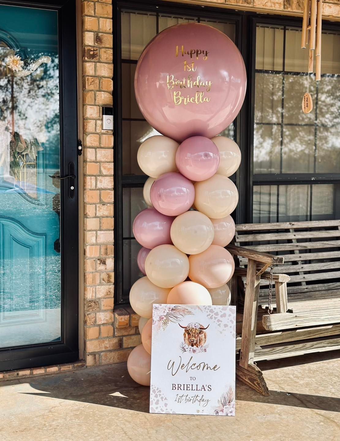 Balloon column with a welcome sign for a party. Featuring pink and cream balloons, and a sign with a Highland cow.