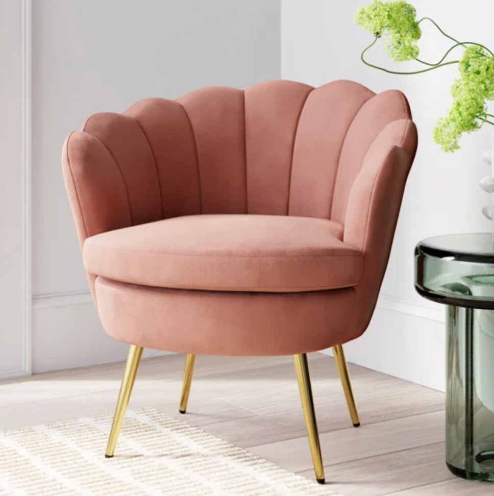 Pink velvet seashell chair with gold legs, in a room.