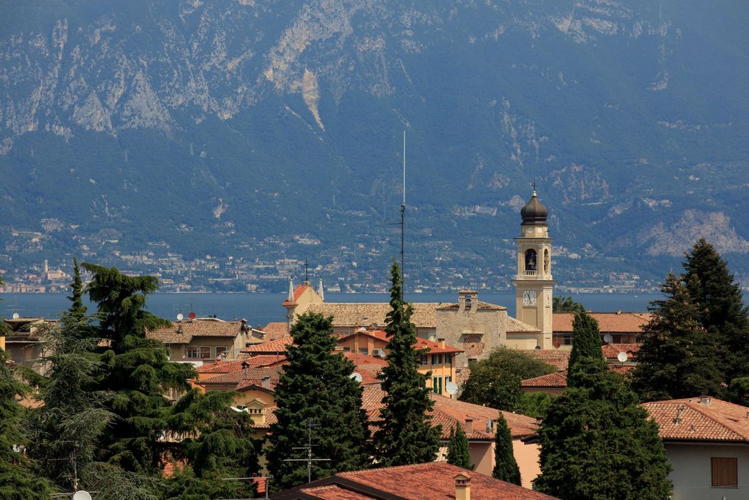 Stadtdächer und ein Kirchturm vor einer dunstigen blauen Bergkulisse