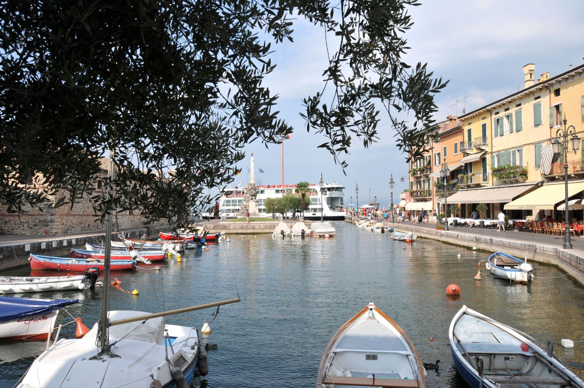 Harbor canal with small boats, waterfront buildings, and trees along the shore