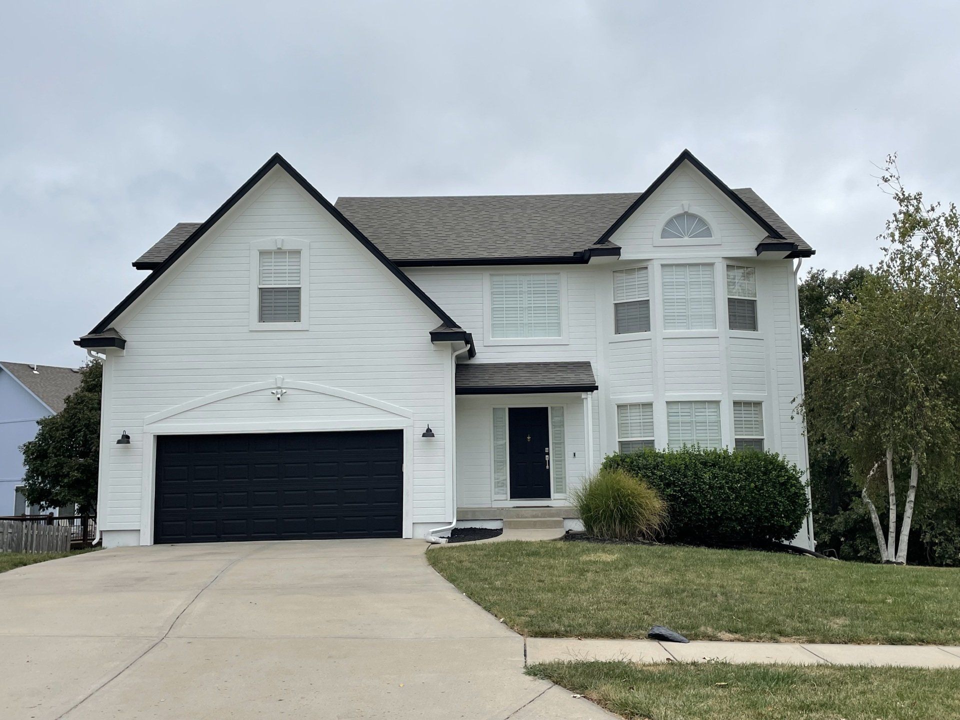A large white house with a black garage door