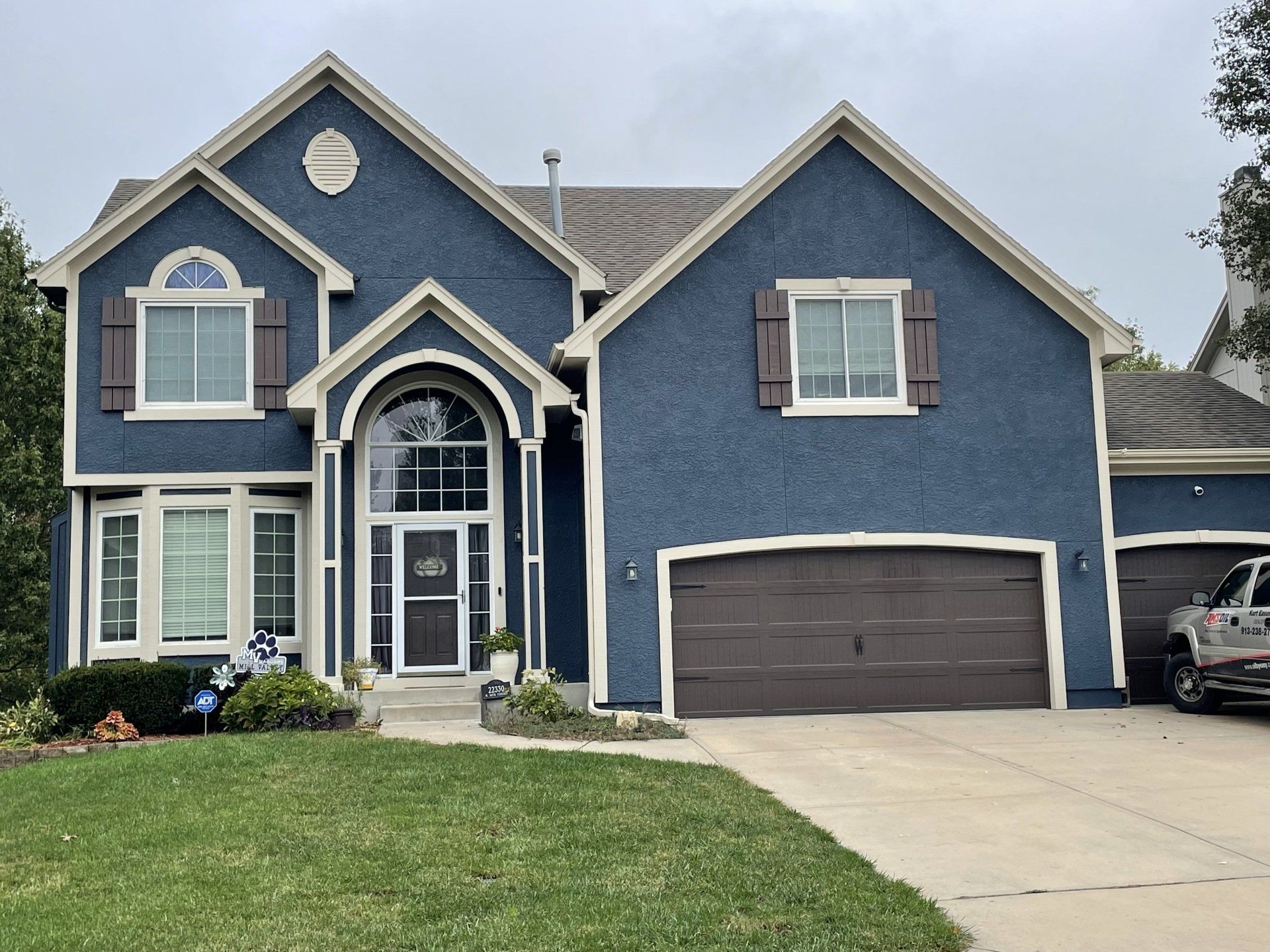 A large blue house with a truck parked in front of it.