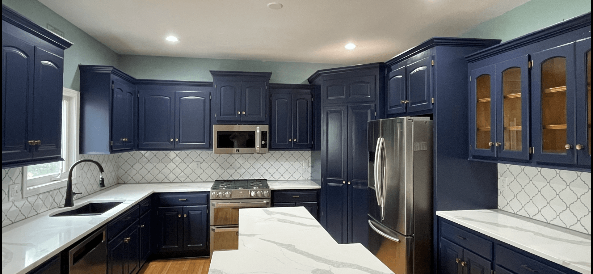 A kitchen with blue cabinets and white counter tops.