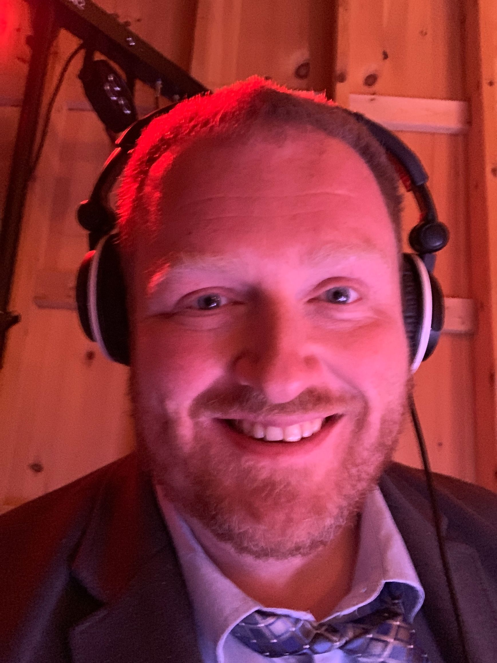 A man with a beard is wearing headphones and smiling.