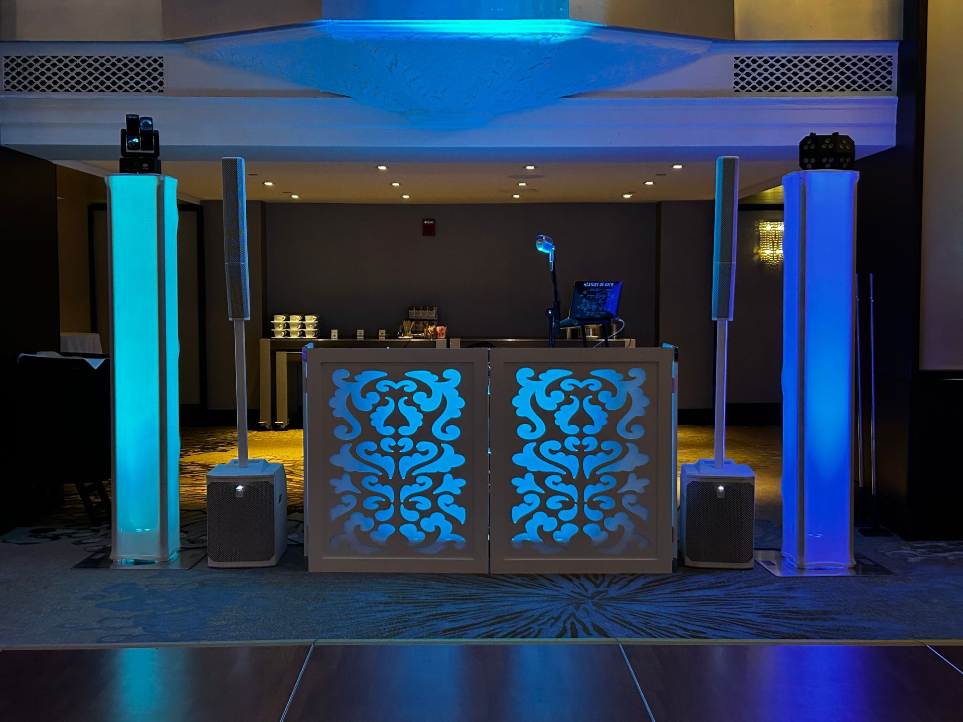 A dj booth is lit up with blue lights in a room.
