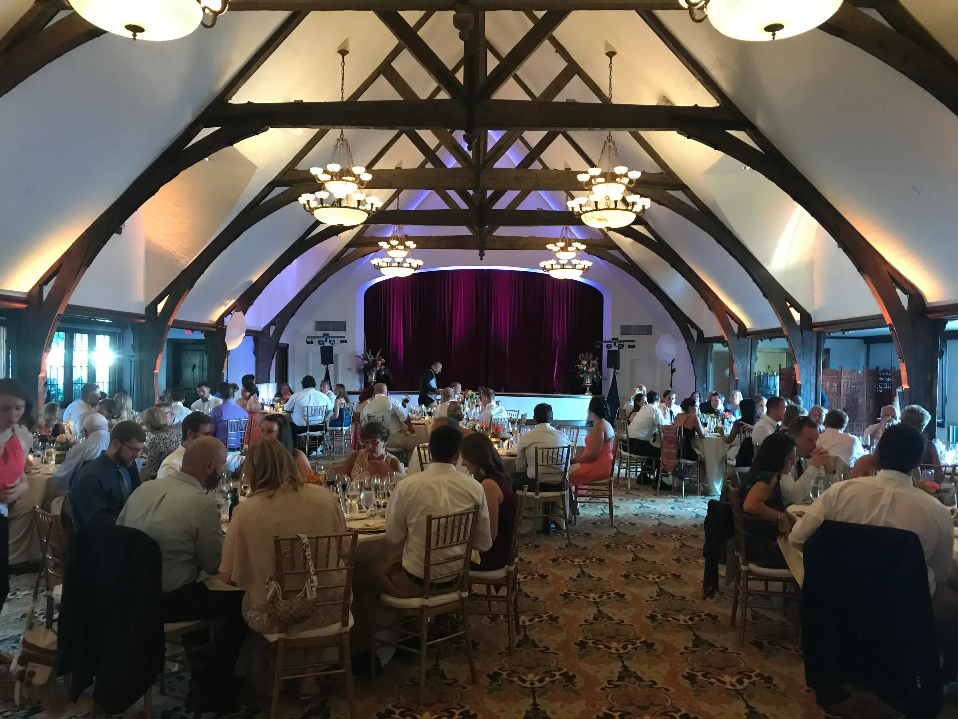 a large room filled with people sitting at tables in front of a stage .