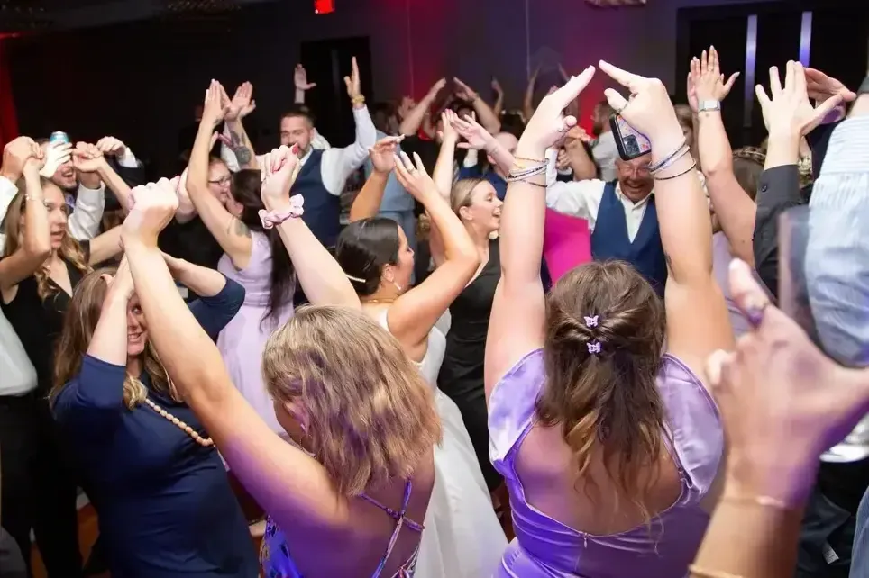 Folks dancing at a party with their hands in the air accompanied by Detonator DJ Services in Maine