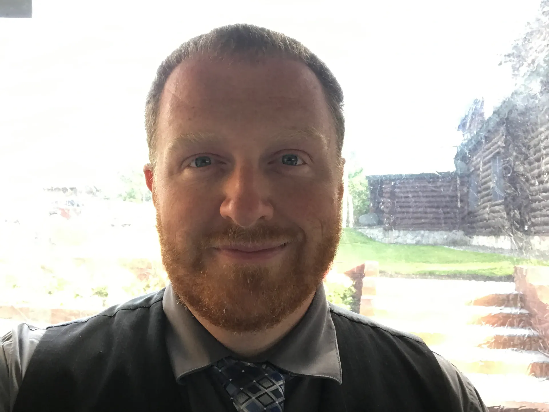 A man with a beard and tie is smiling for the camera.