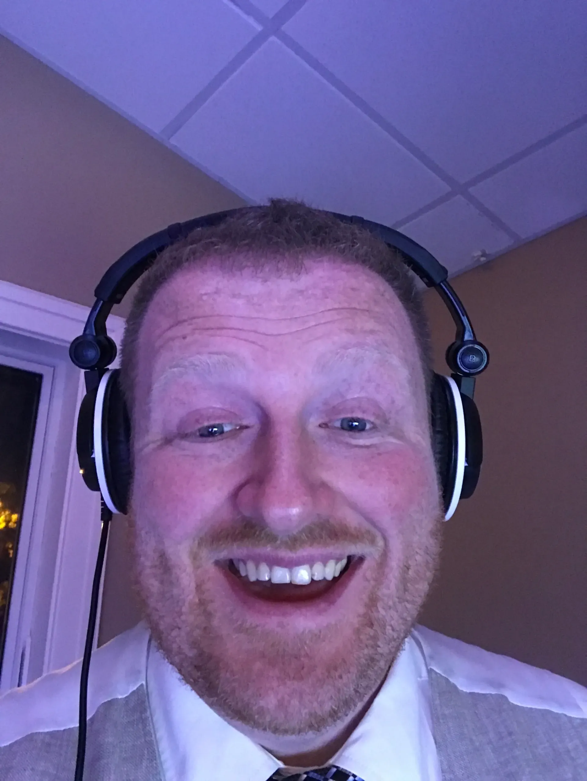 A man wearing headphones is smiling for the camera