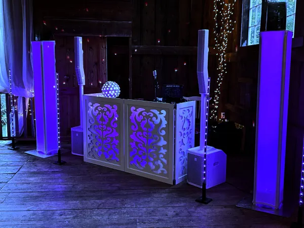 A dj booth is lit up with purple lights in a dark room.