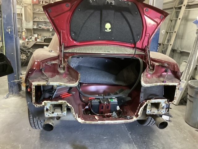 A red car with the trunk open in a garage