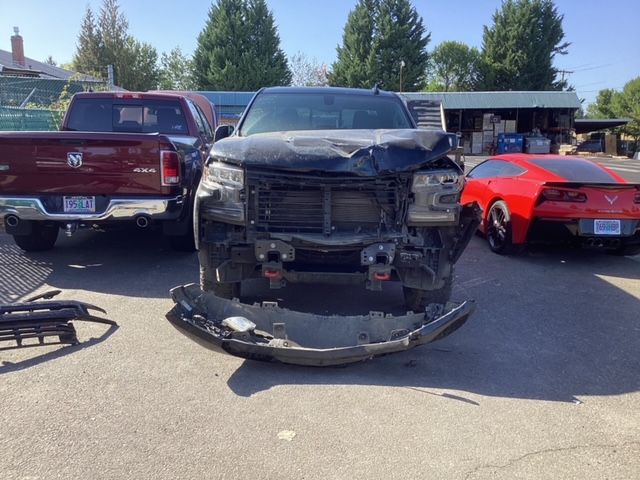 A truck with a damaged front end is parked next to a red car.
