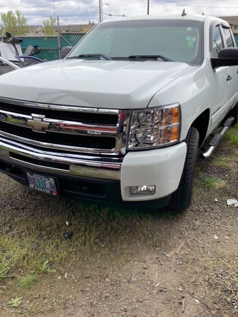A white chevrolet truck is parked in a dirt lot.