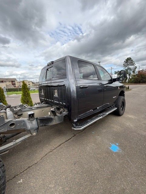 A black truck with a trailer attached to it is parked in a parking lot.