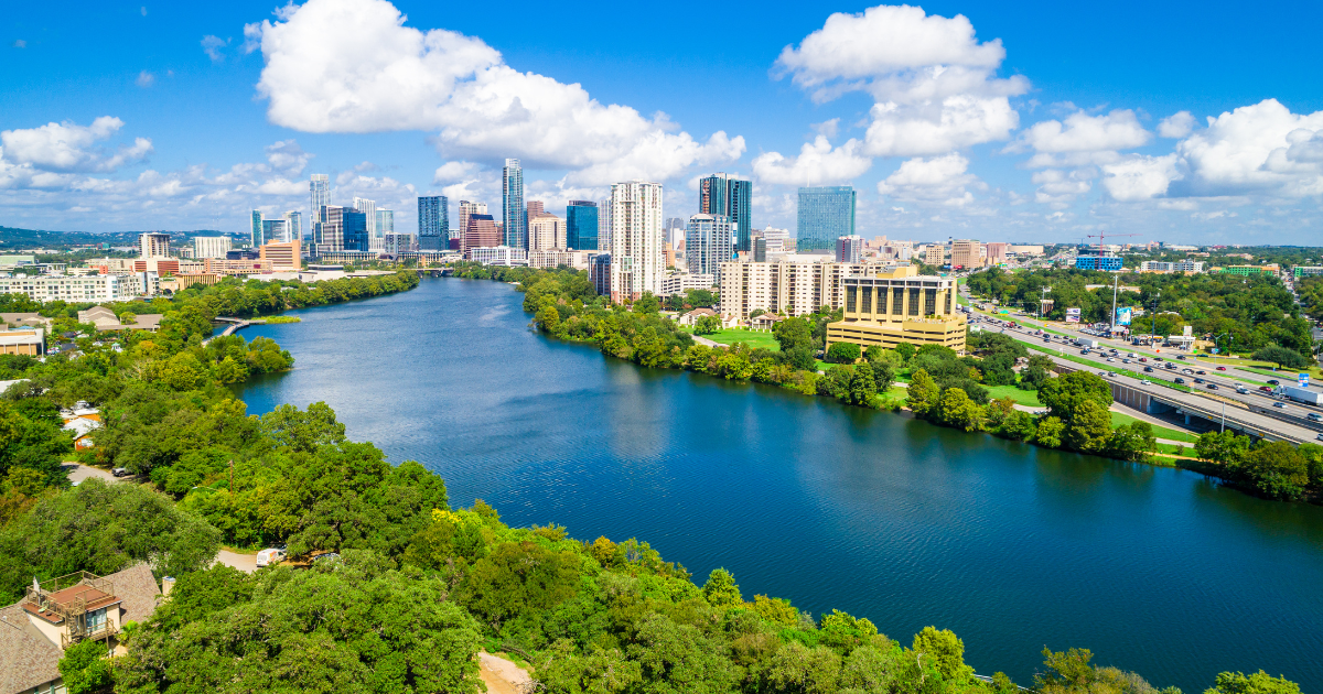 An aerial view of a lake with a city skyline in the background.